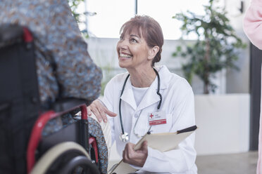Arzt lächelt den Patienten im Rollstuhl an - ZEF007248