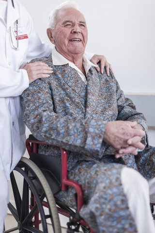 Arzt und lächelnder älterer Patient im Rollstuhl, lizenzfreies Stockfoto