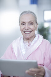 Smiling elderly woman in hospital corridor with digital tablet - ZEF007267