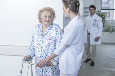 Nurse leading elderly patient with walking frame on hospital floor - ZEF007271