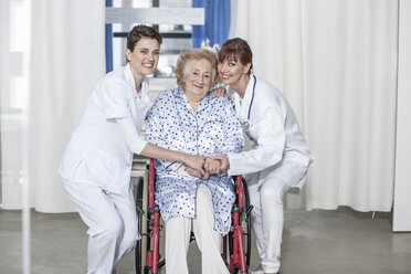 Arzt und Krankenschwester kümmern sich um einen älteren Patienten im Rollstuhl - ZEF007276