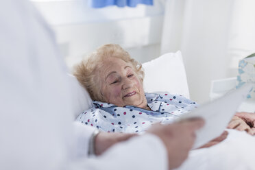 Doctor showing digital tablet to elderly patient in hospital bed - ZEF007277