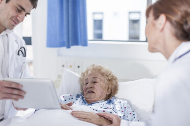 Doctor showing digital tablet to elderly patient in hospital bed - ZEF007278