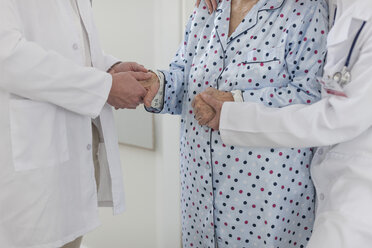 Zwei Ärzte halten die Hände eines älteren Patienten - ZEF007282