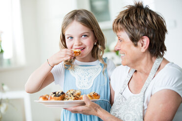 Großmutter und Enkelin in der Küche mit einem Teller mit Gebäck - WESTF021516