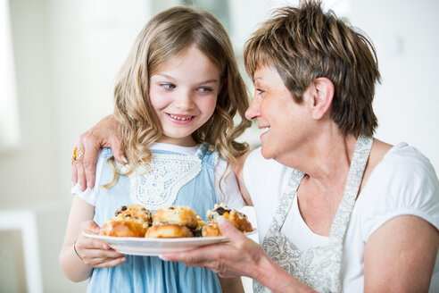 Großmutter und Enkelin in der Küche mit einem Teller mit Gebäck - WESTF021517