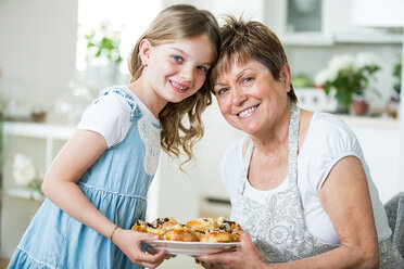 Großmutter und Enkelin in der Küche mit einem Teller mit Gebäck - WESTF021519