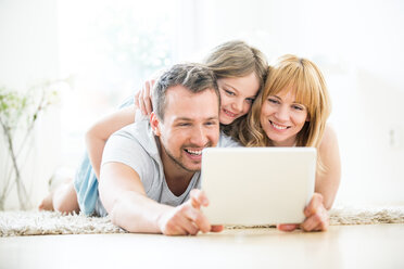 Glückliche Familie auf dem Boden liegend mit digitalem Tablet - WESTF021525