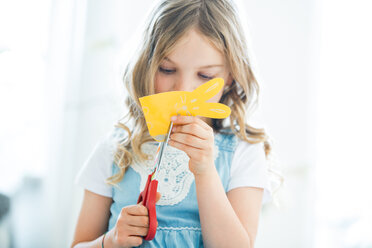 Kleines Mädchen schneidet Osterhasen aus Papier aus - WESTF021544