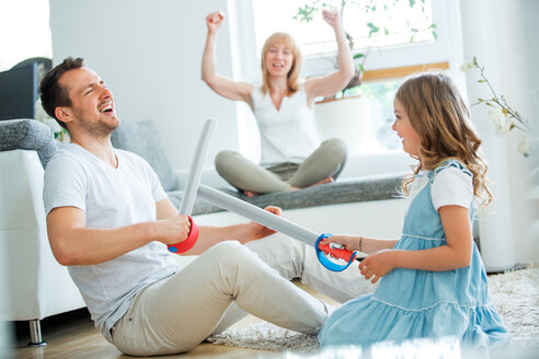 Vater und Tochter kämpfen mit Spielzeugschwertern, die Mutter jubelt im Hintergrund - WESTF021549