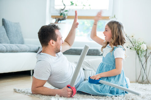 Vater und Tochter spielen mit Spielzeugschwertern und geben sich die Hand - WESTF021552