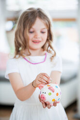 Girl throwing coin into piggy bank - WESTF021566