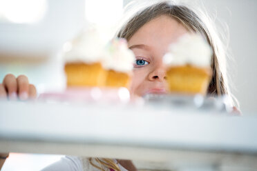 Mädchen schaut gierig durch Tassenkuchen - WESTF021570