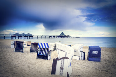 Germany, Heringsdorf, view to sea bridge with hooded beach chairs on the beach in the foreground - PUF000395