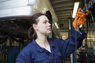 Junge Frau arbeitet in einer Reparaturwerkstatt mit einem elektrischen Schraubenzieher - SGF001807