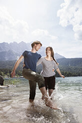 Germany, Bavaria, Eibsee, happy couple splashing in water - RBF003003