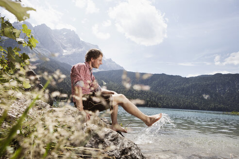 Germany, Bavaria, Eibsee, smiling man in lederhosen splashing in water - RBF003006