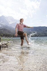 Deutschland, Bayern, Eibsee, fröhlicher Mann in Lederhosen beim Planschen im Wasser - RBF003010