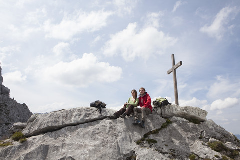 Deutschland, Bayern, Osterfelderkopf, Ehepaar rastet am Gipfelkreuz, lizenzfreies Stockfoto