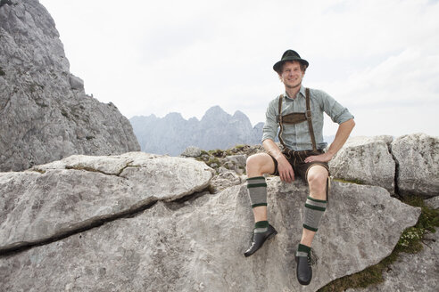 Germany, Bavaria, Osterfelderkopf, man in traditional clothes sitting in mountain landscape - RBF003024