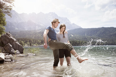 Germany, Bavaria, Eibsee, happy couple splashing in water - RBF003047