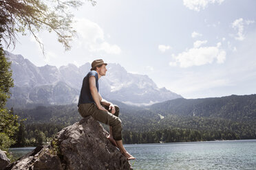 Deutschland, Bayern, Eibsee, Mann sitzt auf Felsen am Seeufer - RBF003048