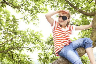 Girl dressed up as pirate sitting on a tree looking out - MFRF000283