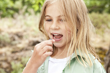 Blond girl eating a blueberry - MFRF000280