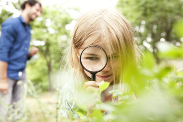 Mädchen in der Natur schaut durch ein Vergrößerungsglas - MFRF000277