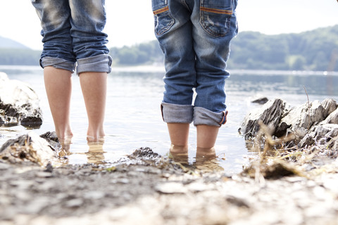 Close-up of two children standing at lakeshore stock photo