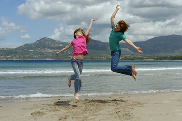 Frankreich, Korsika, Calvi, zwei Kinder springen am Strand in die Luft - LBF001156