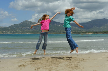 France, Corsica , Calvi, two children jumping in the air on the beach - LBF001155