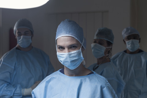 Portrait of surgeon wearing mask with team in background stock photo