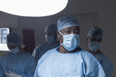 Porträt eines Chirurgen mit Maske und Team im Hintergrund - ZEF007383