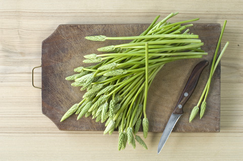 Wilder Spargel und Küchenmesser auf Holzbrett, lizenzfreies Stockfoto