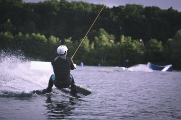 Back view of young man wakeboarding - MADF000505