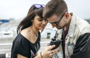 Spanien, Gijon, junges Paar schaut sich Bilder auf dem Smartphone an - MGOF000406