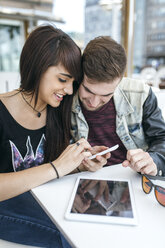 Spanien, Gijon, junges Paar schaut sich Bilder auf dem Smartphone an - MGOF000398