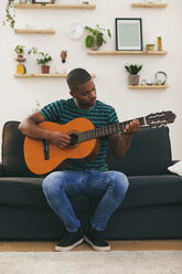 Man sitting on a couch playing guitar - EBSF000849