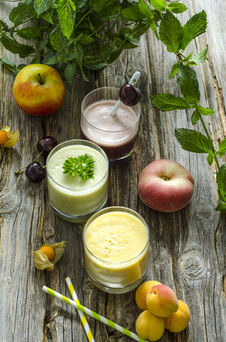 Kirsch-Smoothie, Aprikosen-Pfirsich-Smoothie, Petersilien-Minze-Smoothie und Früchte, lizenzfreies Stockfoto