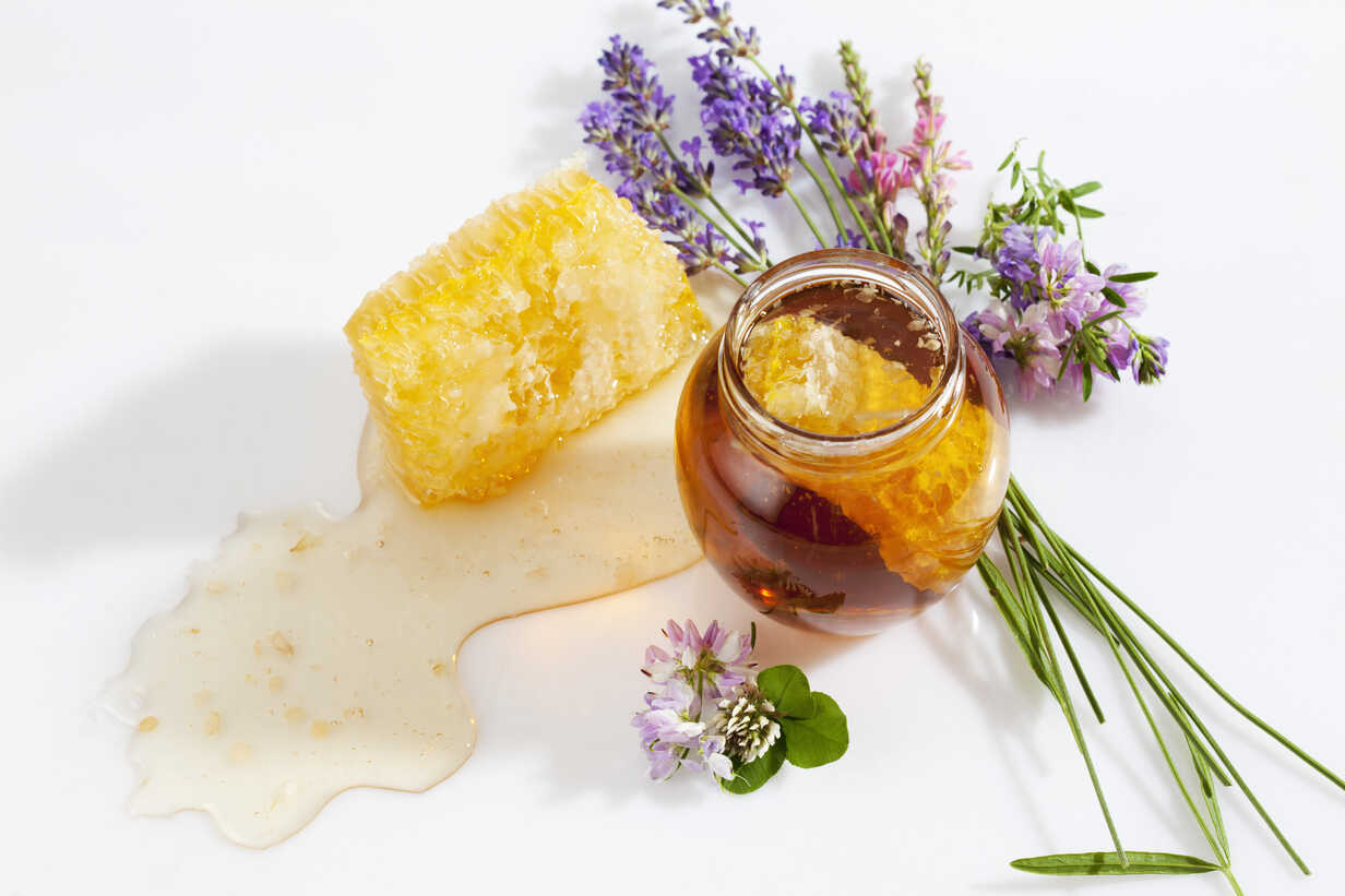 Glass of honey, honeycomb and wild flowers stock photo