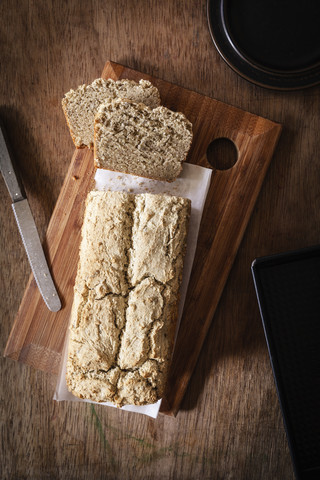 Home-baked wholemeal bread, gluten-free, bread knife, slices of bread on chopping board stock photo