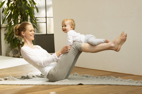 Frau balanciert Baby auf ihren Beinen - ABF000629