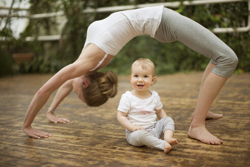 Woman doing yoga exercise while baby watching her - ABF000631