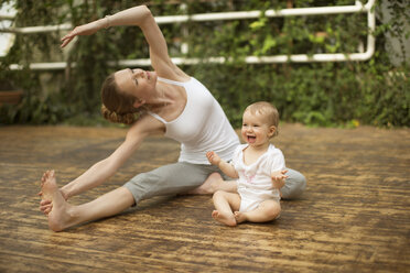 Woman doing yoga exercise while baby having fun - ABF000632