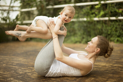 Frau balanciert Baby auf ihren Beinen - ABF000634