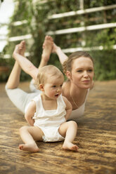 Frau macht Yoga-Übungen, während das Baby daneben sitzt - ABF000636