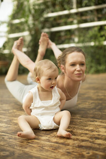 Frau macht Yoga-Übungen, während das Baby daneben sitzt - ABF000636