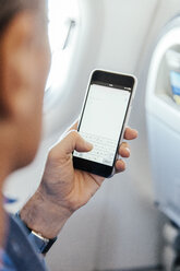 Mann sitzt in einem Flugzeug und tippt auf seinem Smartphone - MFF001988