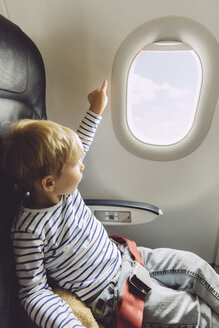 Kleiner Junge, der aus einem Flugzeugfenster zeigt - MFF001995